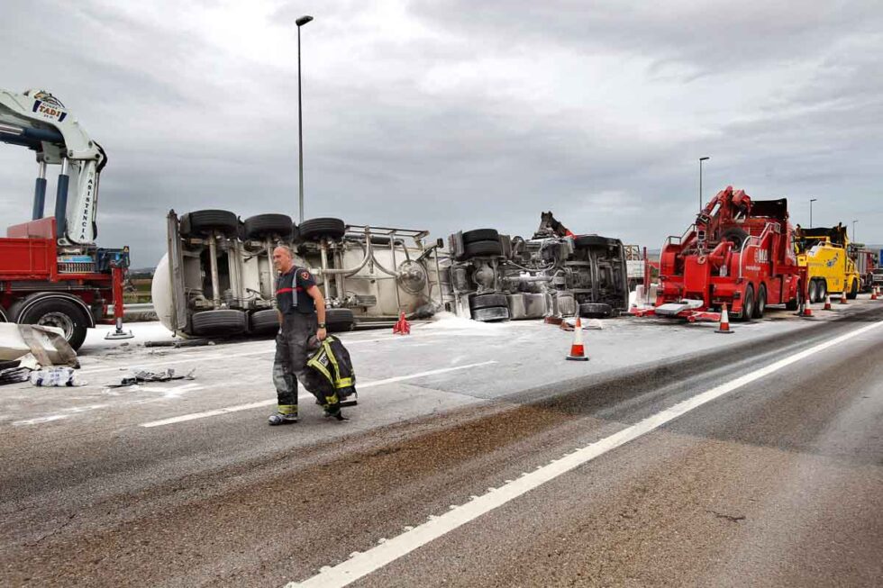 Bomberos terminando los servicios de limpieza tras un accidente de un camión volcado