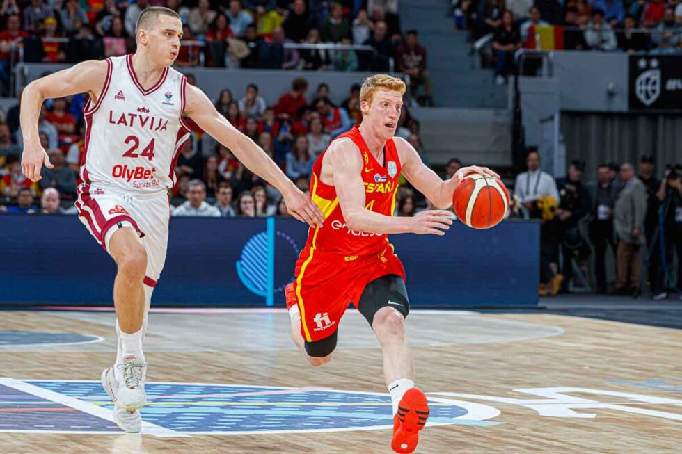 Momento de acción en un partido de baloncesto entre un jugador de España y otro de Letonia