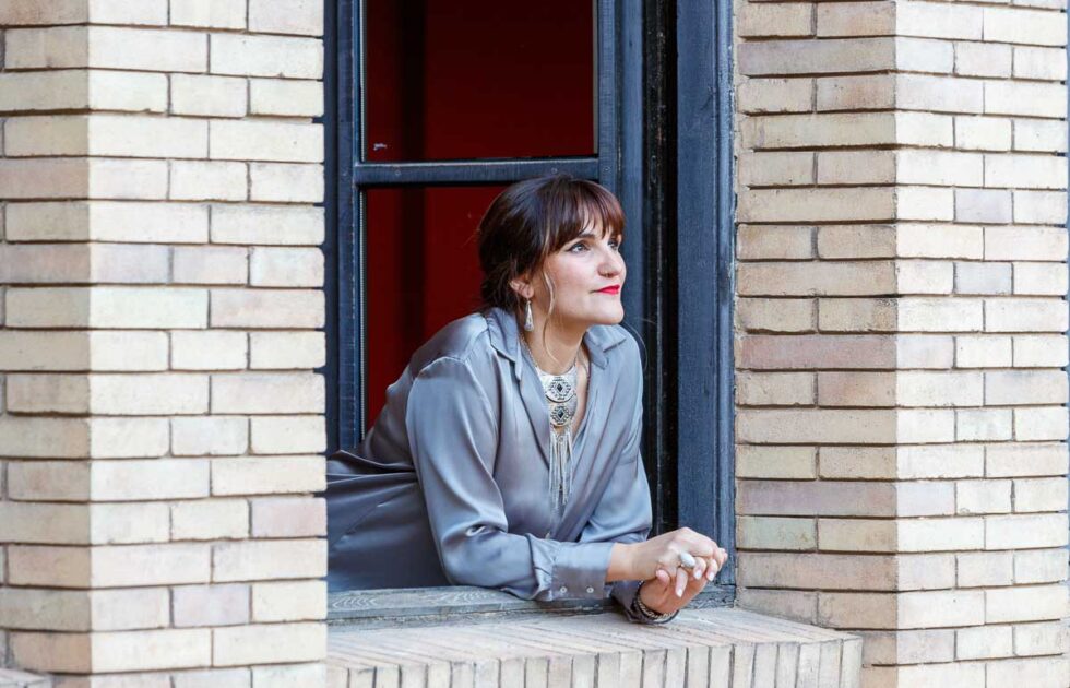 Retrato de la cantante Rozalén asomada a una ventana con gesto sonriente