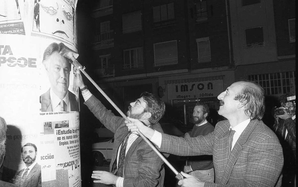 Fotografia en blanco y negro con el ministro Cosculluela pegando carteles antes de las elecciones