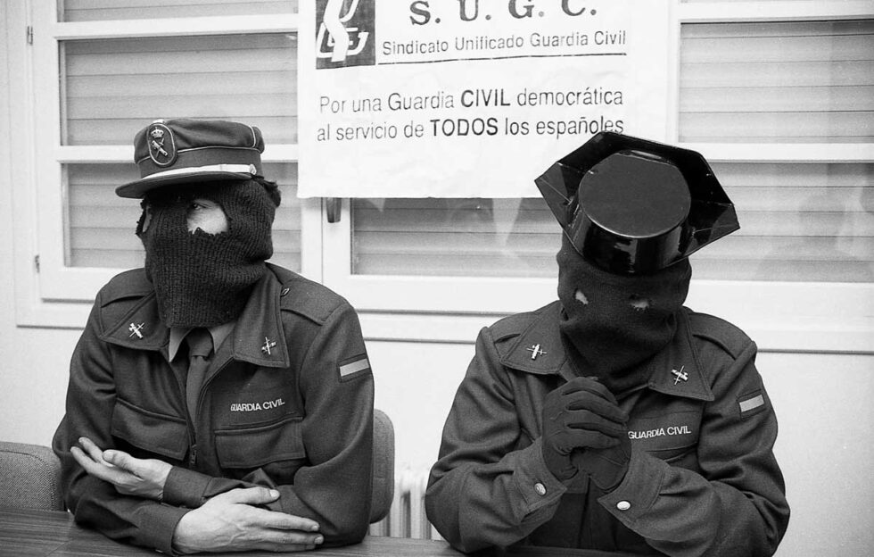 Fotografía en blanco y negro de dos guardias civiles encapuchados durante una reunión de la S.U.G.C.