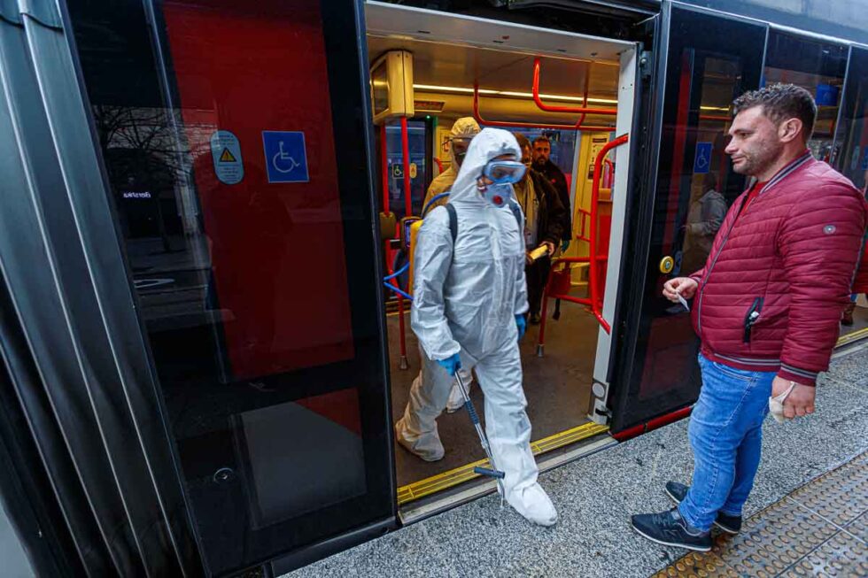 El tranvía abre sus puertas para dejar salir a dos trabajadores equipados con EPIs tras desinfectar el interior del tranvía