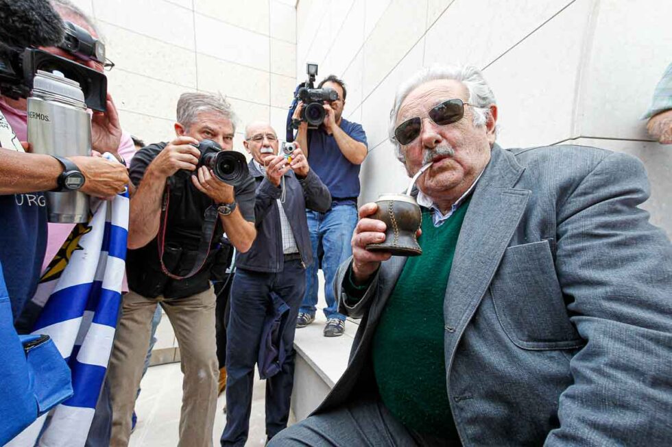 José Mújica bebiendo mate y mirando a cámara, alrededor varios fotógrafos